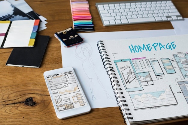 Homepage wireframes sketched in a notebook beside a phone